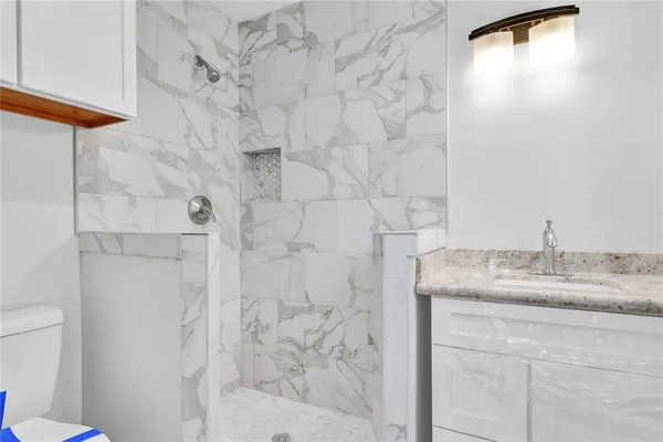 a bathroom with a granite countertop sink and a toilet