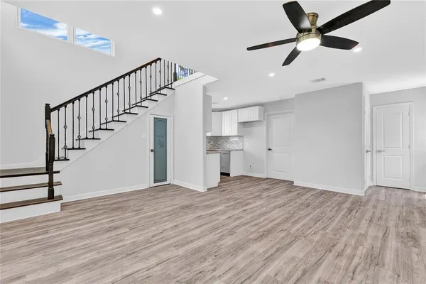 a view of an empty room with wooden floor and a ceiling fan