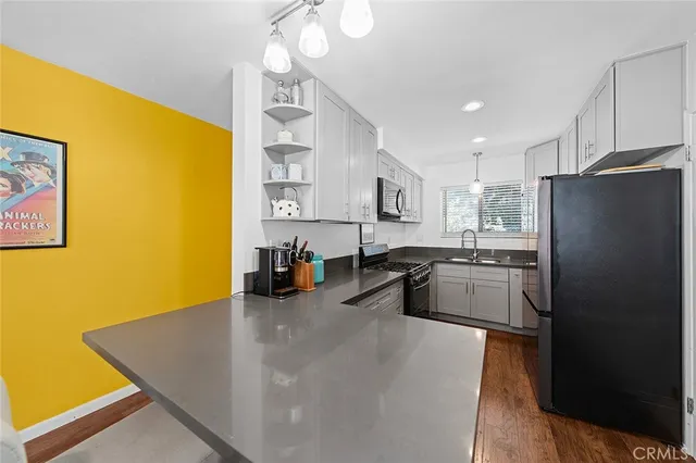 a kitchen with stainless steel appliances granite countertop a refrigerator a sink a stove and a refrigerator with wooden floor