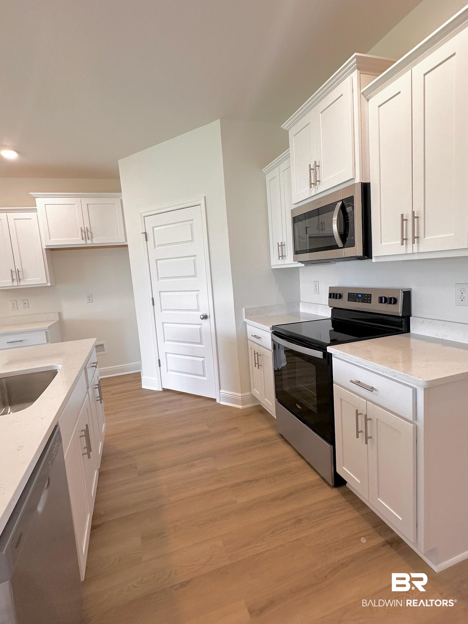 12946 Grand Rpds Road Fairhope, AL 36532 - Photo 2 of 19 Kitchen featuring appliances with stainless steel finishes, light hardwood / wood-style flooring, white cabinets, and light stone counters