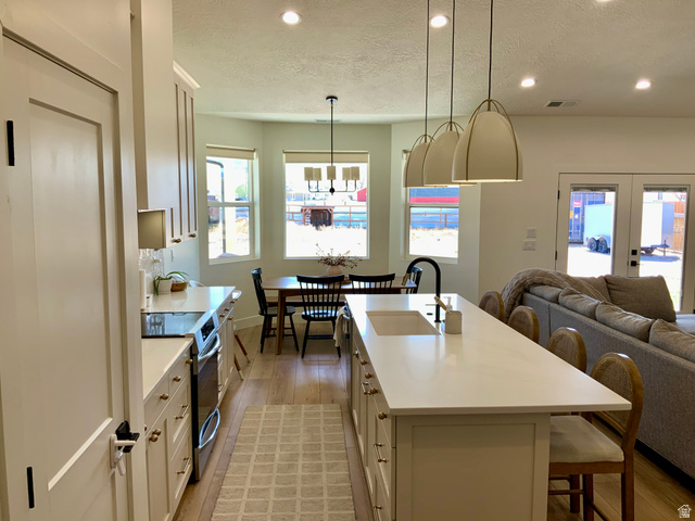 277 West 800 South Monroe, UT 84754 - Photo 7 of 46 Kitchen featuring a kitchen bar, stainless steel electric range, light wood-style floors, a kitchen island with sink, and white cabinetry