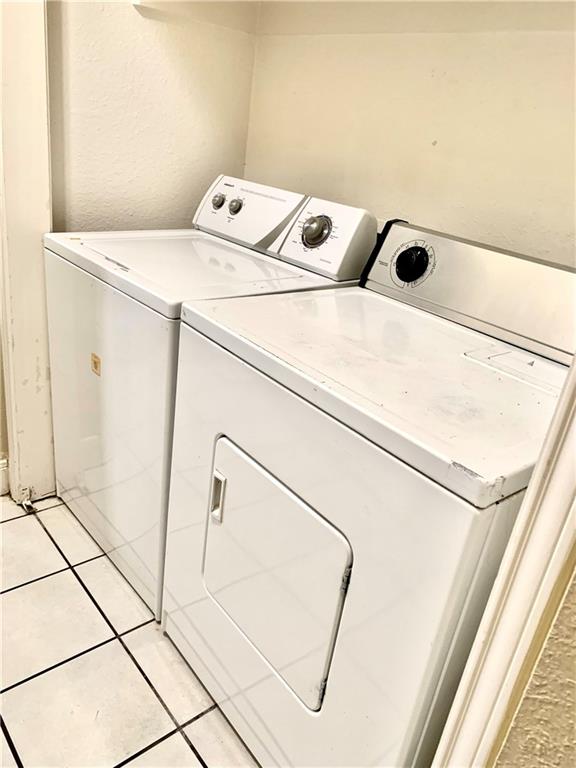 503 East 38th Street, Unit B Austin, TX 78705 - Photo 11 of 11 Laundry area featuring washer and dryer, a textured wall, and light tile patterned floors