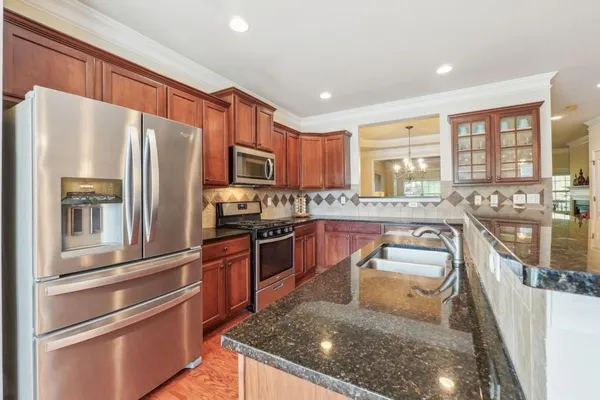 a kitchen with stainless steel appliances granite countertop a refrigerator a stove top oven a sink and dishwasher