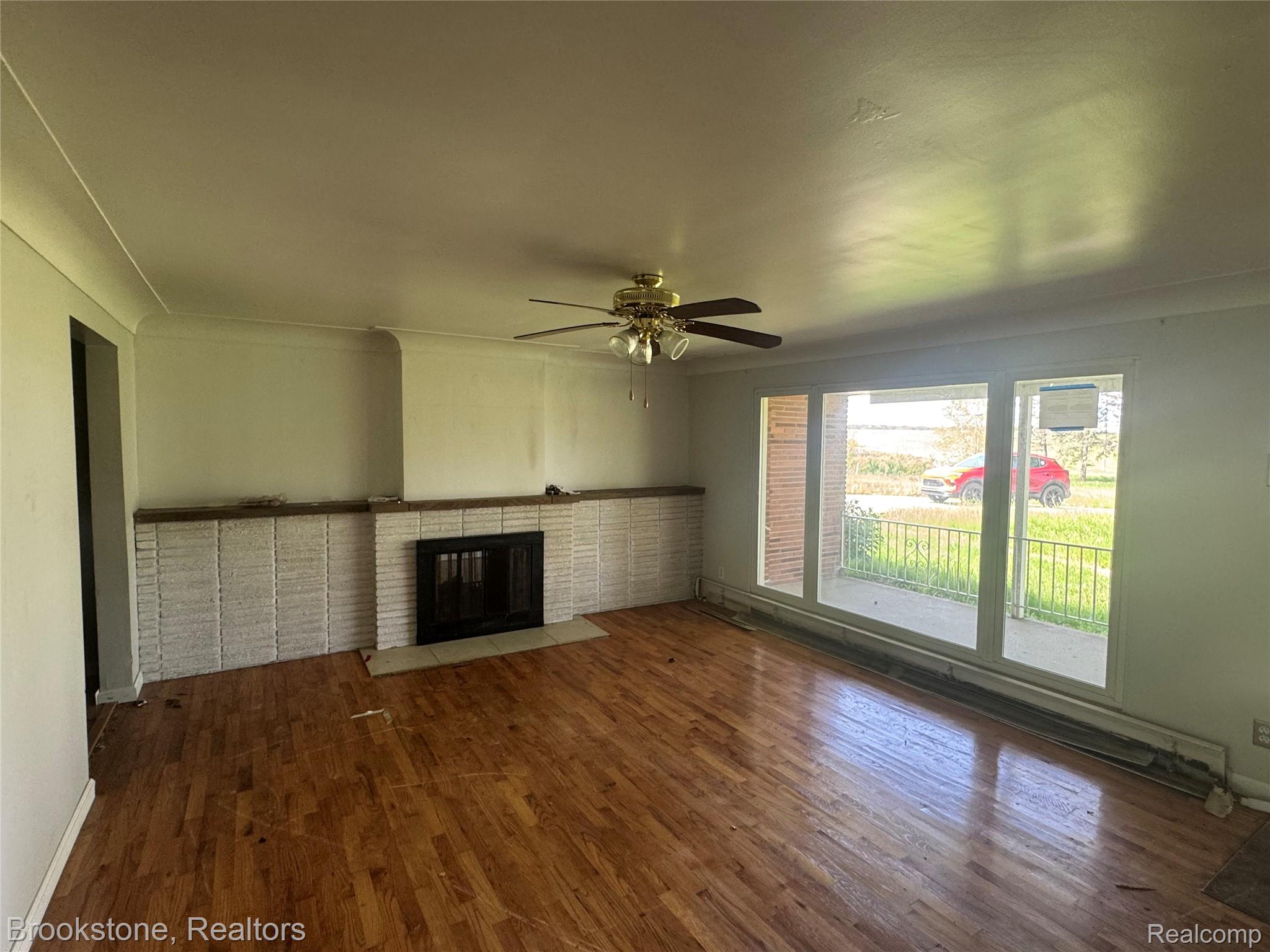 3055 Atlas Road Davison, MI 48423 - Photo 6 of 13 Living area featuring wood-finish flooring, a white brick fireplace with a dark metal insert, and a wood mantel