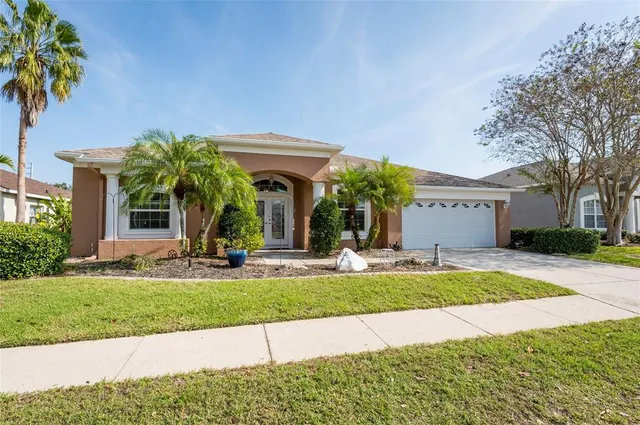 a view of a house with a yard and palm trees