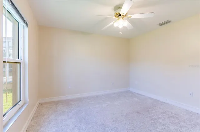 an empty room with fan and windows