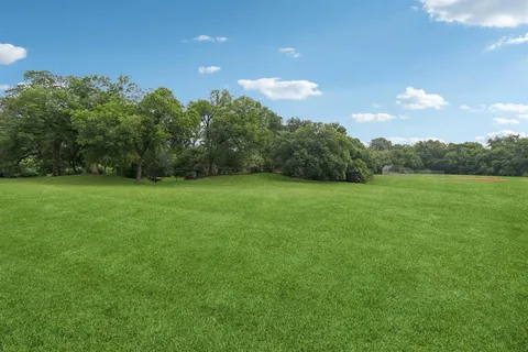 a view of a green field with trees in the background