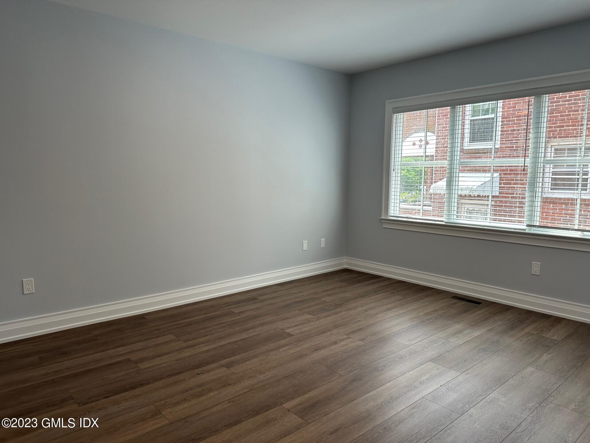 104 Pemberwick Road, Unit 1 Greenwich, CT 06831 - Photo 11 of 18 an empty room with wooden floor and windows