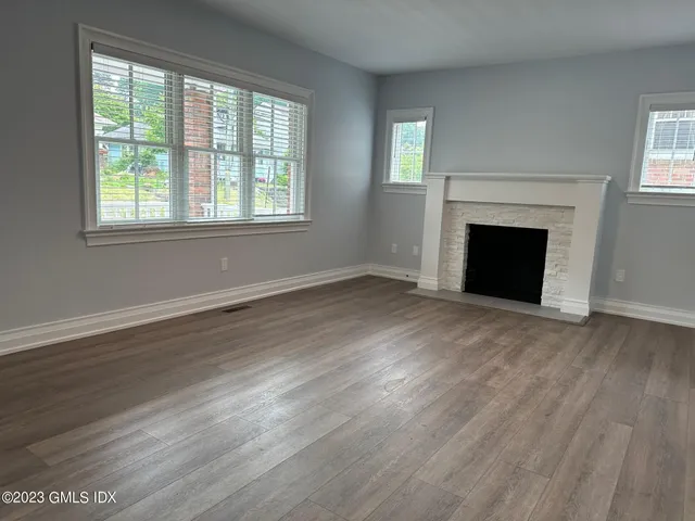 an empty room with wooden floor fireplace and windows
