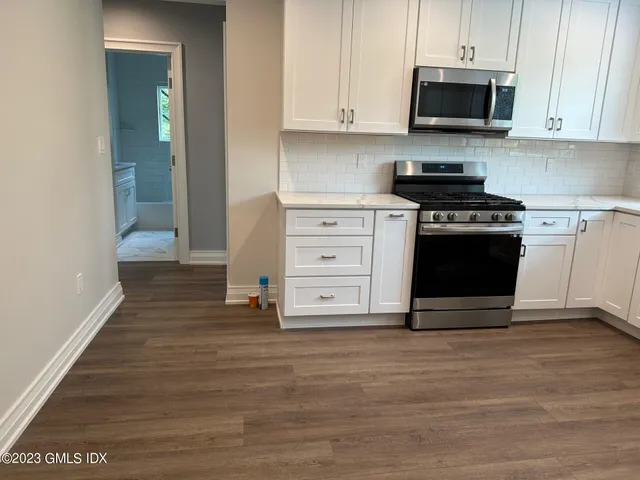a kitchen with stainless steel appliances white cabinets and a stove top oven