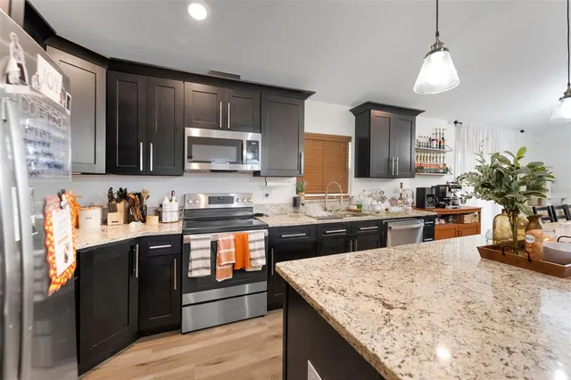 a kitchen with stainless steel appliances granite countertop wooden cabinets a stove top oven a granite counter top and a sink