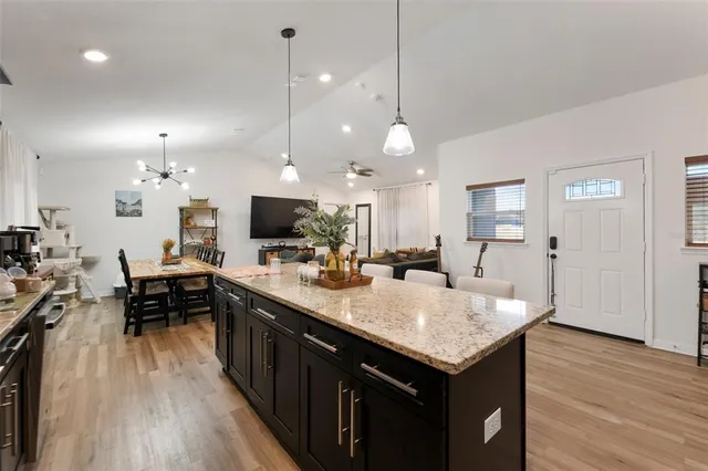 a kitchen with a center island wooden floor appliances and a view of living room