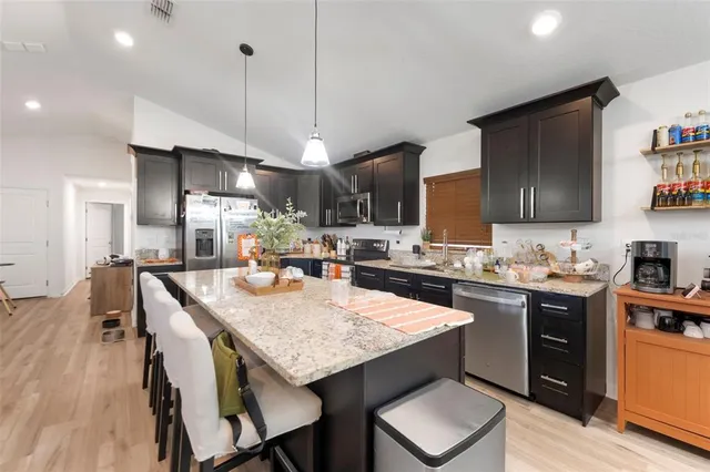 a kitchen with stainless steel appliances granite countertop a kitchen island a stove a table and chairs in it