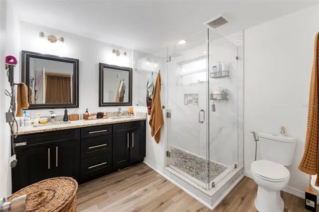 a bathroom with a sink vanity granite toilet and a shower
