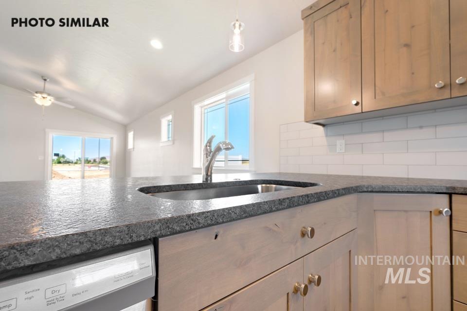 1693 Rapid Road Emmett, ID 83617 - Photo 14 of 28 Kitchen featuring a stainless steel sink, dark textured countertops, light wood-finish cabinetry, subway tile backsplash, and an integrated dishwasher