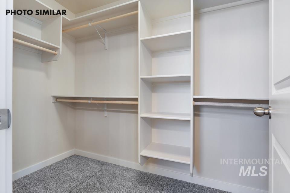 1693 Rapid Road Emmett, ID 83617 - Photo 18 of 28 Walk-in closet featuring built-in shelving, multiple hanging rods, white trim, and gray carpet flooring