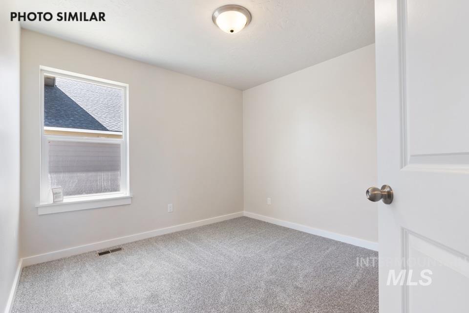 1693 Rapid Road Emmett, ID 83617 - Photo 20 of 28 Neutral-toned room featuring a single window with white trim, light gray wall-to-wall carpeting, and a flush-mount ceiling light fixture