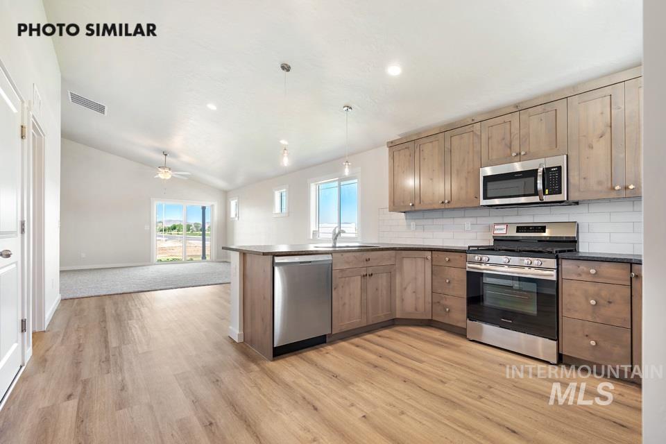 1693 Rapid Road Emmett, ID 83617 - Photo 8 of 28 Open-concept kitchen featuring light wood-finish cabinetry, stainless steel appliances, and a white subway tile backsplash