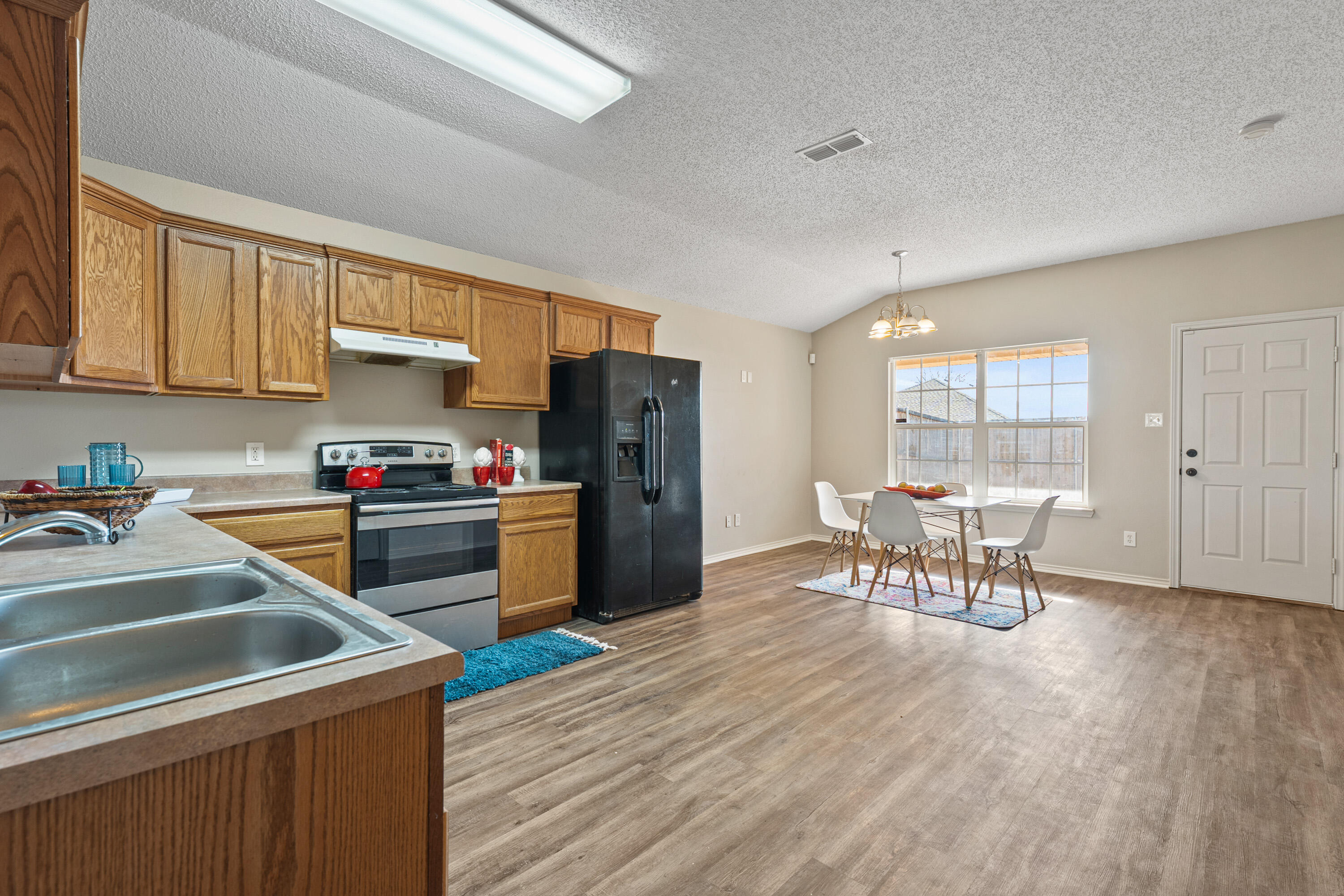 6517 91st Street Lubbock, TX 79424 - Photo 4 of 11 a kitchen with a table chairs refrigerator and cabinets