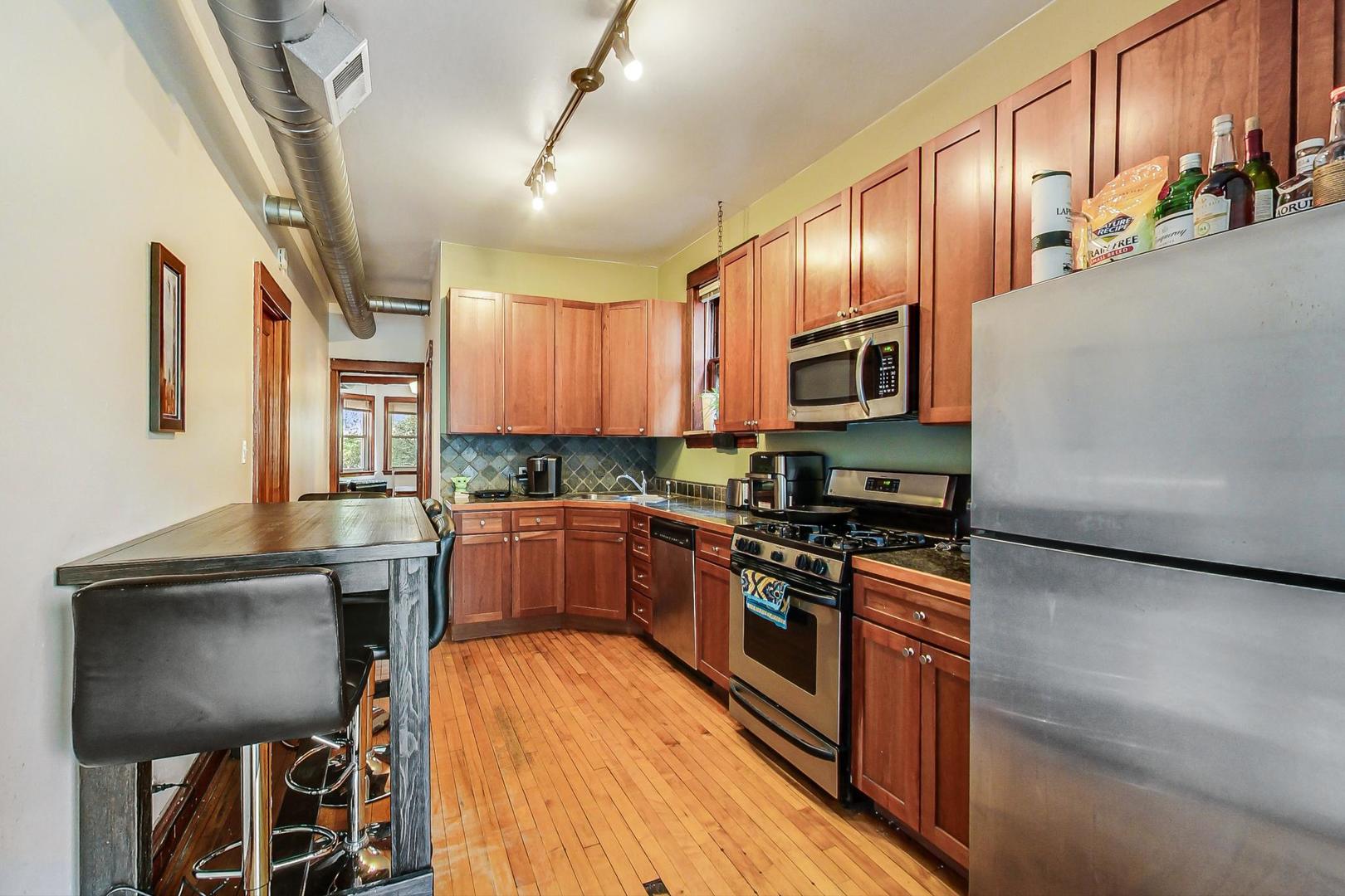 2145 West Thomas Street, Unit 2 Chicago, IL 60622 - Photo 8 of 14 a kitchen with stainless steel appliances granite countertop wooden cabinets a stove top oven a sink and dishwasher