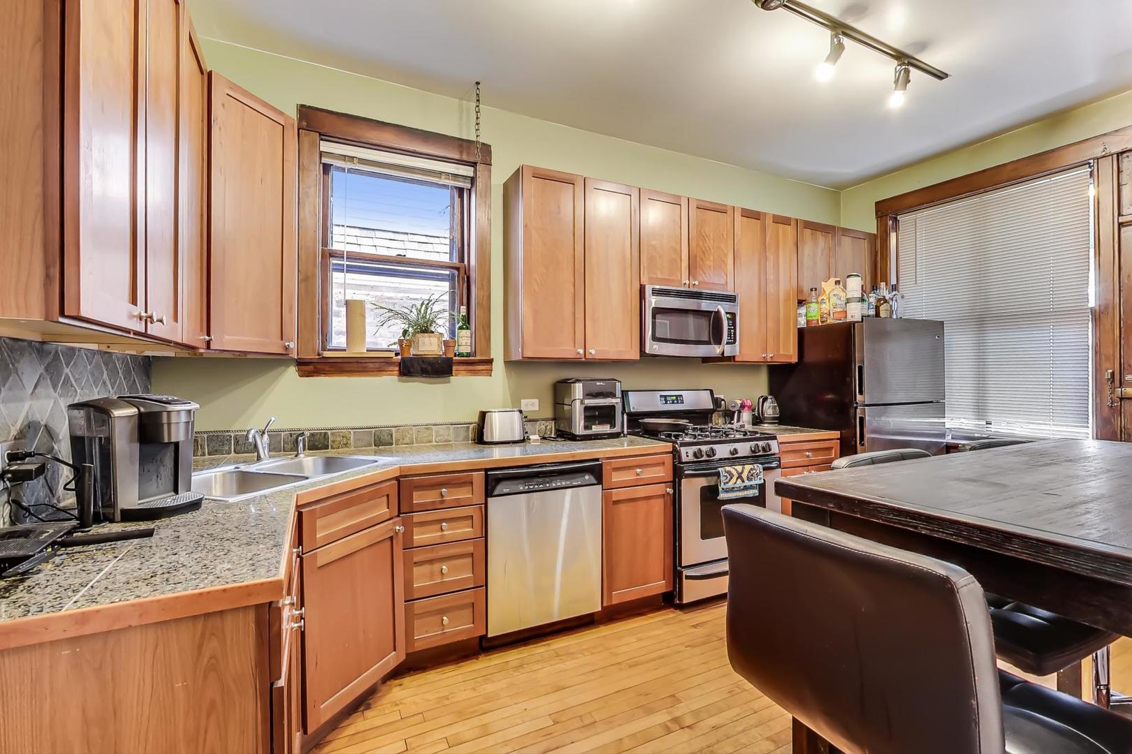 2145 West Thomas Street, Unit 2 Chicago, IL 60622 - Photo 9 of 14 a kitchen with stainless steel appliances granite countertop wooden cabinets microwave and stove top oven