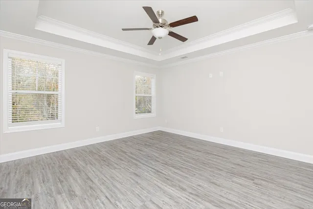 an empty room with wooden floor ceiling fan and windows