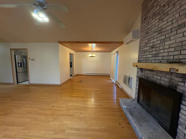 a view of an empty room with wooden floor and a fireplace