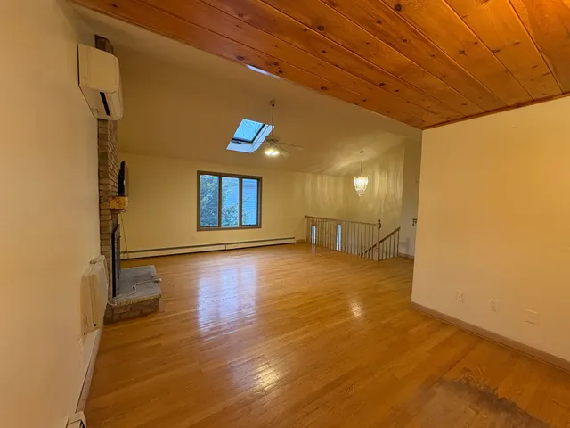 a view of an empty room with window and wooden floor