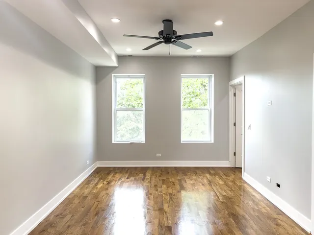 a view of empty room with wooden floor and fan
