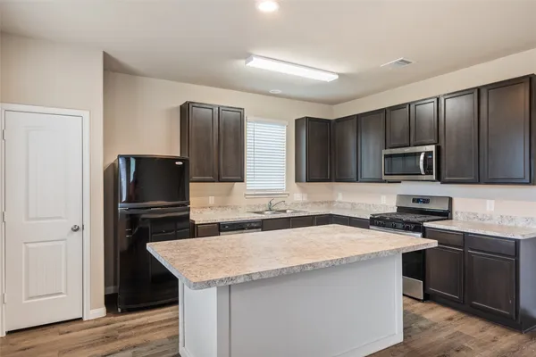 a kitchen with a sink a microwave a refrigerator and cabinets