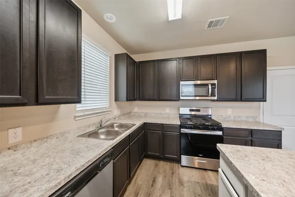 a kitchen with stainless steel appliances granite countertop a sink stove and refrigerator