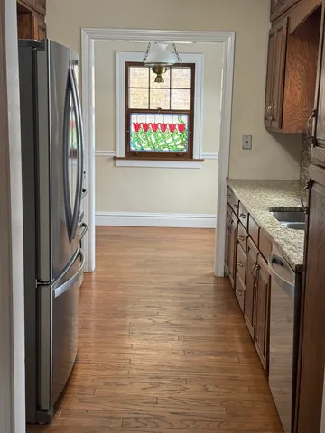 a kitchen with stainless steel appliances granite countertop a refrigerator a stove and a wooden floors