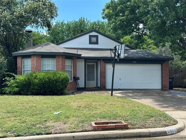 a view of a house with a yard plants and large tree