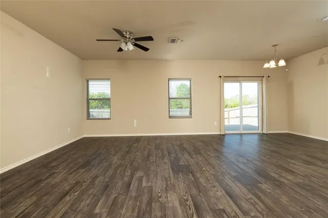 an empty room with wooden floor fan and windows