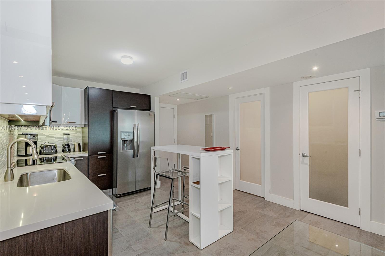 2301 Collins Avenue, Unit 723 Miami Beach, FL 33139 - Photo 20 of 26 a view of a kitchen with refrigerator and chairs