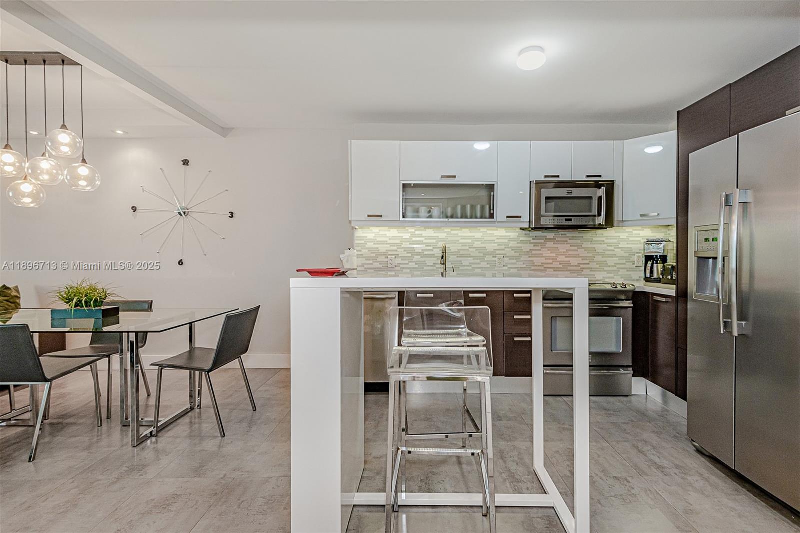 2301 Collins Avenue, Unit 723 Miami Beach, FL 33139 - Photo 21 of 26 a kitchen with stainless steel appliances kitchen island granite countertop a table and chairs in it