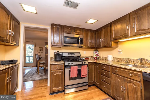 a kitchen with stainless steel appliances granite countertop wooden cabinets a stove top oven a sink and dishwasher