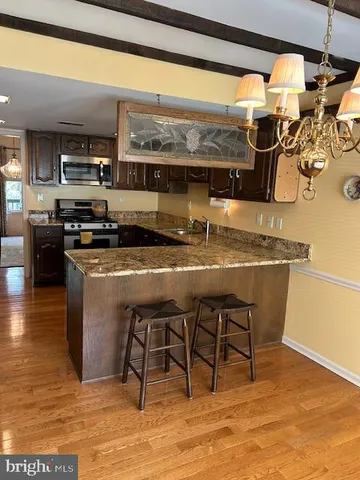 a kitchen with stainless steel appliances granite countertop a table chairs in it and wooden floors