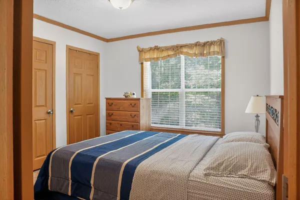 a bedroom with a bed a dresser and a window