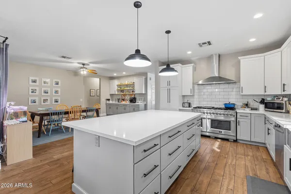 a large kitchen with kitchen island a stove a sink a center island and a wooden floor