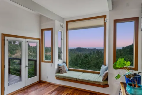 a view of a room with a large window and wooden floor