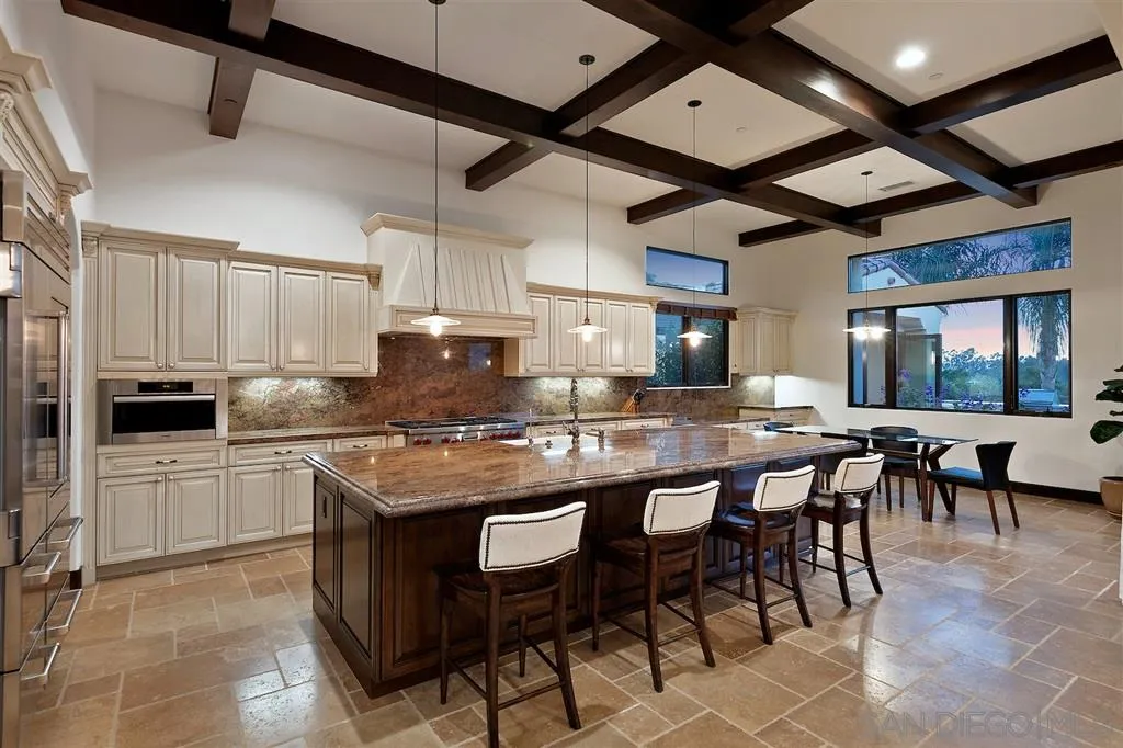 6806 St Andrews Road Rancho Santa Fe, CA 92067 - Photo 6 of 25 a kitchen with stainless steel appliances granite countertop a stove top oven a sink a dining table and chairs