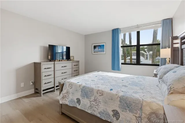 a bedroom with a bed and a flat tv screen on dresser