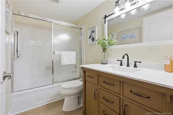 a bathroom with a shower sink vanity mirror and toilet