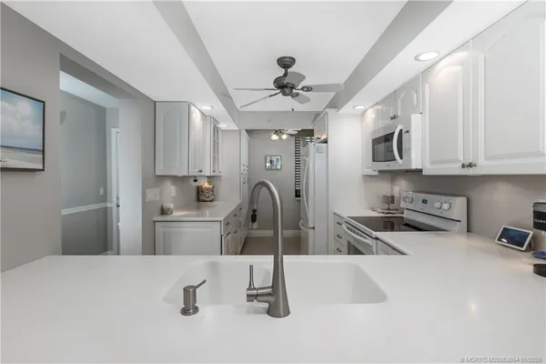 a kitchen with stainless steel appliances a sink a stove a refrigerator cabinets and a window