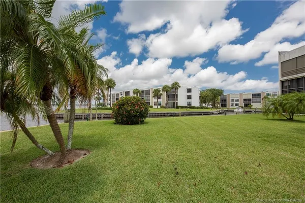 a view of a house with a yard and palm trees