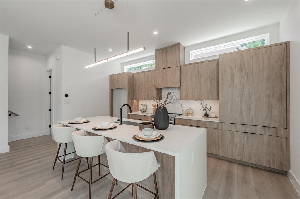5320 Reiger Avenue, Unit 103 Dallas, TX 75214 - Photo 5 of 29 a kitchen with stainless steel appliances kitchen island granite countertop a table chairs and a wooden floor