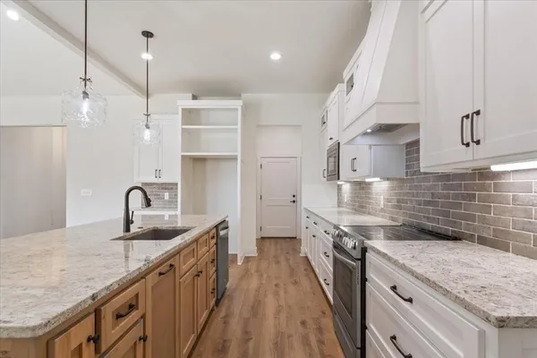 a kitchen with stainless steel appliances granite countertop a sink a stove and a wooden floors