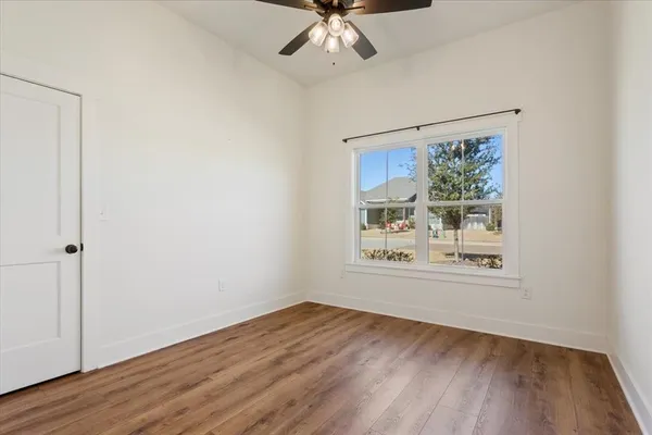 an empty room with wooden floor chandelier and windows