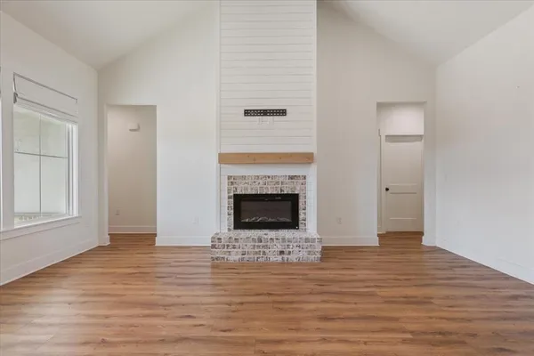 a view of a livingroom with wooden floor and a fireplace